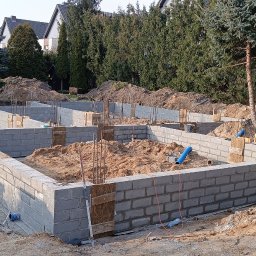 VAH BUD:BUDUIEMO NA VIKY - Fundamenty domu z bloczków betonowych w trakcie budowy, widoczne zbrojenia i szalunki, teren budowy z drzewami w tle.