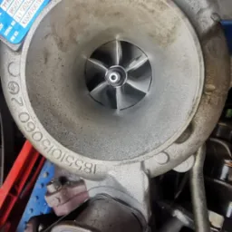 Turbosprężarka Volvo z widocznymi numerami seryjnymi i turbiną. Element silnika samochodowego po regeneracji lub przed montażem, w warsztacie.