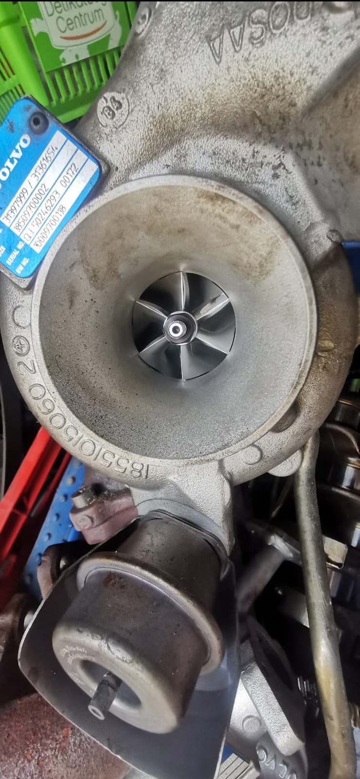 Turbosprężarka Volvo z widocznymi numerami seryjnymi i turbiną. Element silnika samochodowego po regeneracji lub przed montażem, w warsztacie.