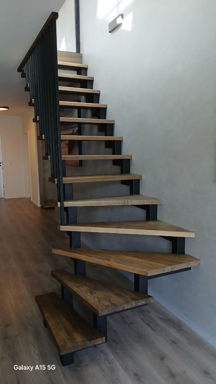 Nowoczesne schody z drewnianymi stopniami i czarną metalową konstrukcją, widok z dołu, minimalistyczny design, jasne wnętrze.