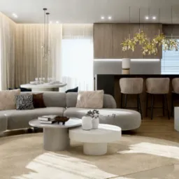 Stylowe wnętrze: szara sofa z poduszkami, okrągłe stoliki kawowe, drewniana zabudowa kuchenna z barkiem. Złote lampy nad blatem, duże okno z zasłonami.