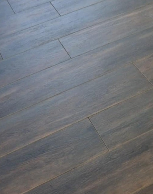 Ułożone, ciemne panele podłogowe z widoczną strukturą drewna, ułożone pod kątem, wypełniające kadr. Widoczne fugi między panelami.