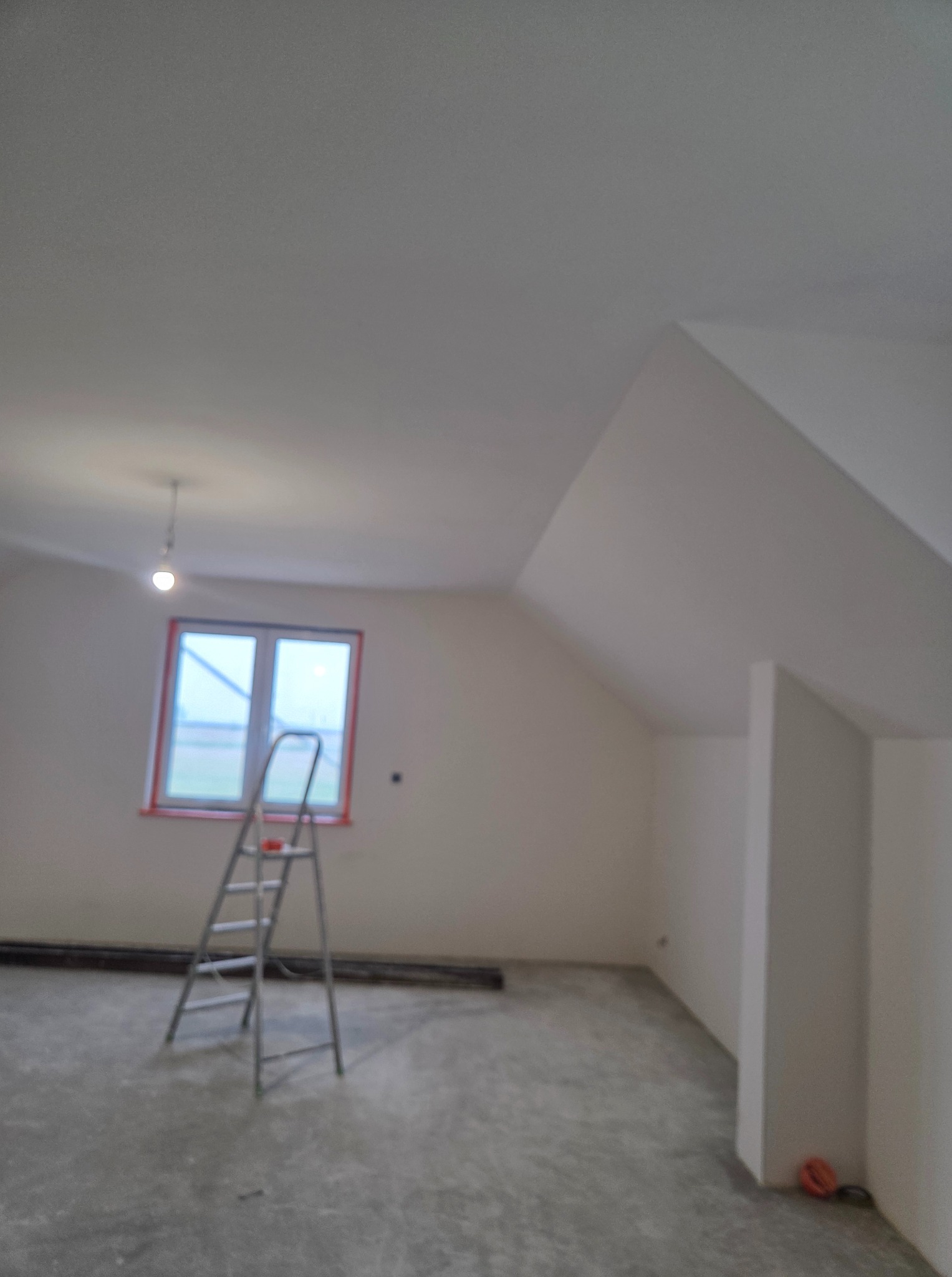 Pokój na poddaszu po szpachlowaniu i malowaniu, z drabiną przy oknie. Ściany białe, surowa podłoga, widoczne listwy przypodłogowe i wisząca żarówka.