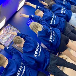 Dwa De Studio - Grupa osób w identycznych, kobaltowych bluzach z kapturem i białym nadrukiem 'KOBALT BARBERSHOP' na plecach, pozujących w niebieskim wnętrzu.