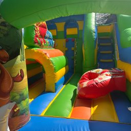 Misja Ruch Malgorzata Zekaj - Kolorowy dmuchany zamek z motywami zwierzęcymi, widok od wewnątrz. Schody, zjeżdżalnia i tunel tworzą atrakcyjny plac zabaw dla dzieci.