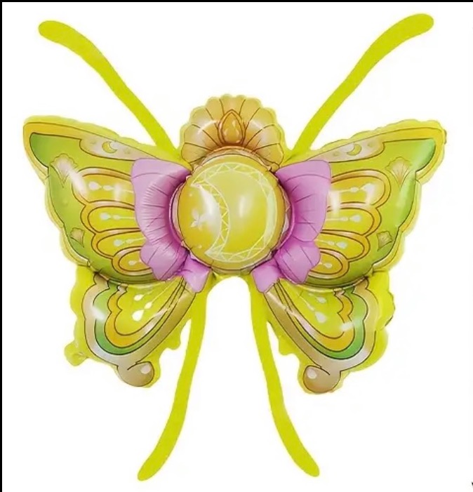 Żółto-zielony balon foliowy w kształcie skrzydeł motyla z różową kokardą i księżycem w środku, na białym tle. Dekoracja na imprezę tematyczną.