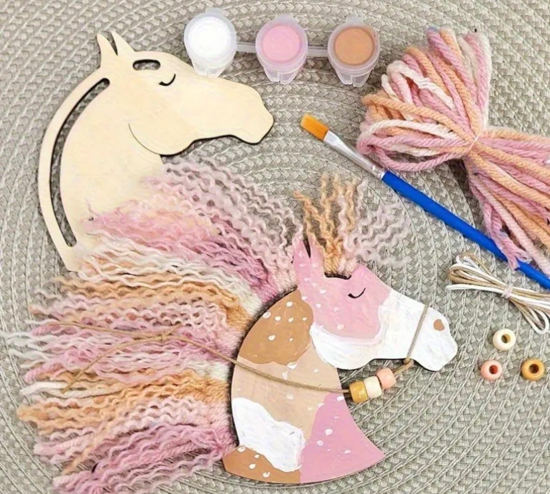 Ręcznie robiony konik z drewna, farb i włóczki w pastelowych kolorach. DIY zestaw kreatywny dla dzieci, leżący na plecionej macie. Widoczne farby, pędzel i koraliki.