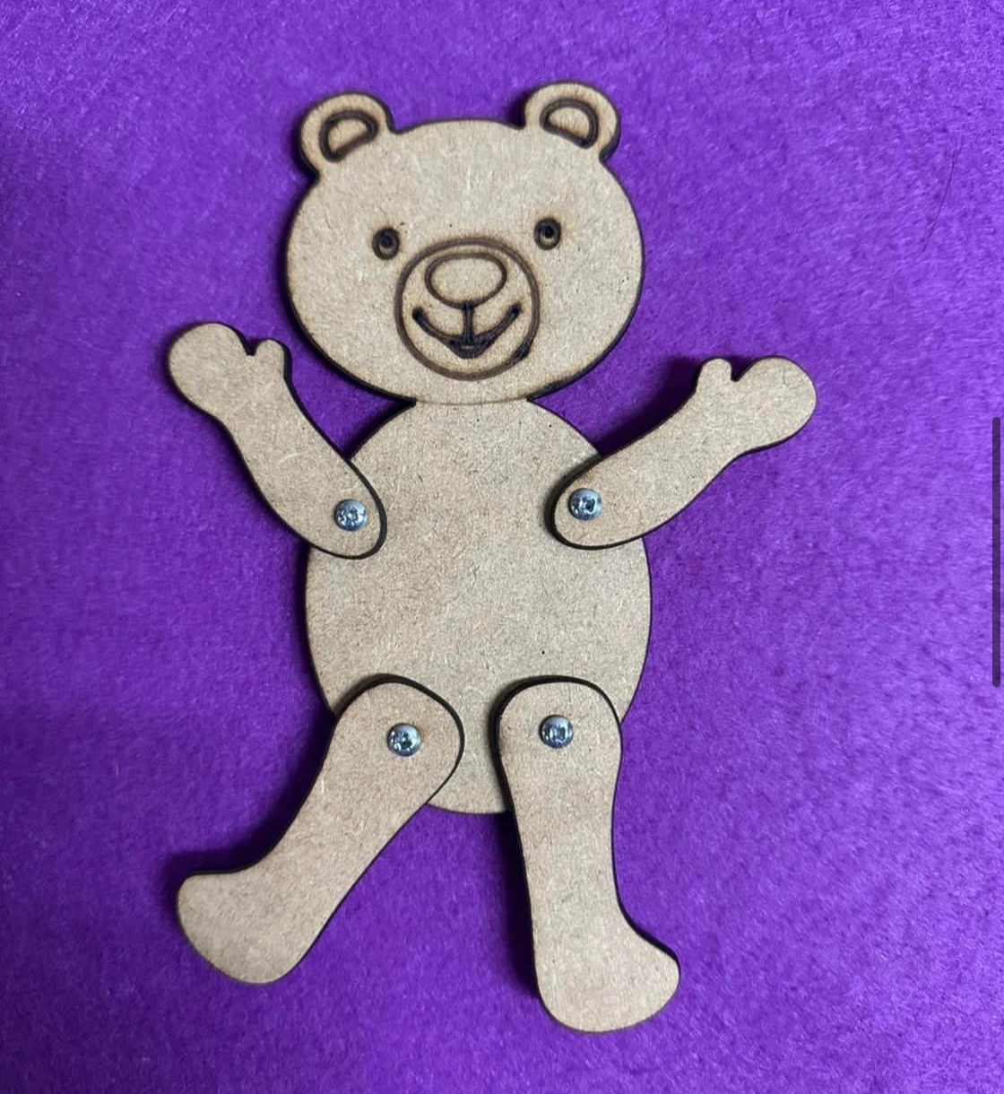 Drewniany, ruchomy miś z łącznikami na fioletowym tle. Zabawka edukacyjna dla dzieci, rękodzieło z drewna, elementy ruchome, widoczne śruby mocujące.