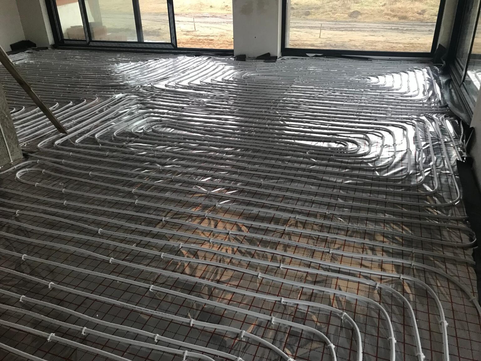 Instalacja ogrzewania podłogowego z rur na folii aluminiowej, widok z góry. Siatka zbrojeniowa, przygotowanie do wylewki.