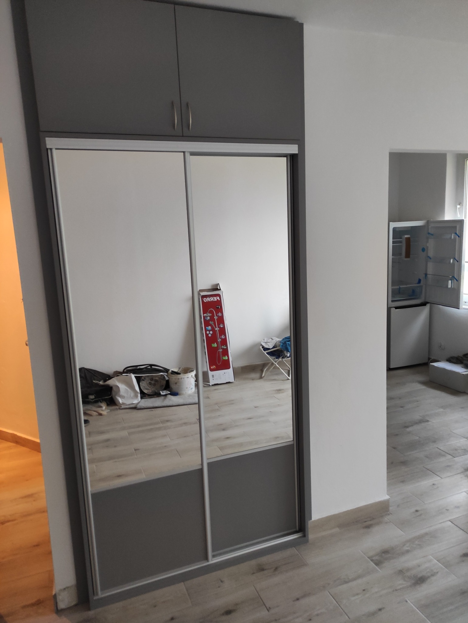 Szafa z lustrem, szare fronty. Montaż we wnęce – lekko wystaje przez płytką zabudowę.