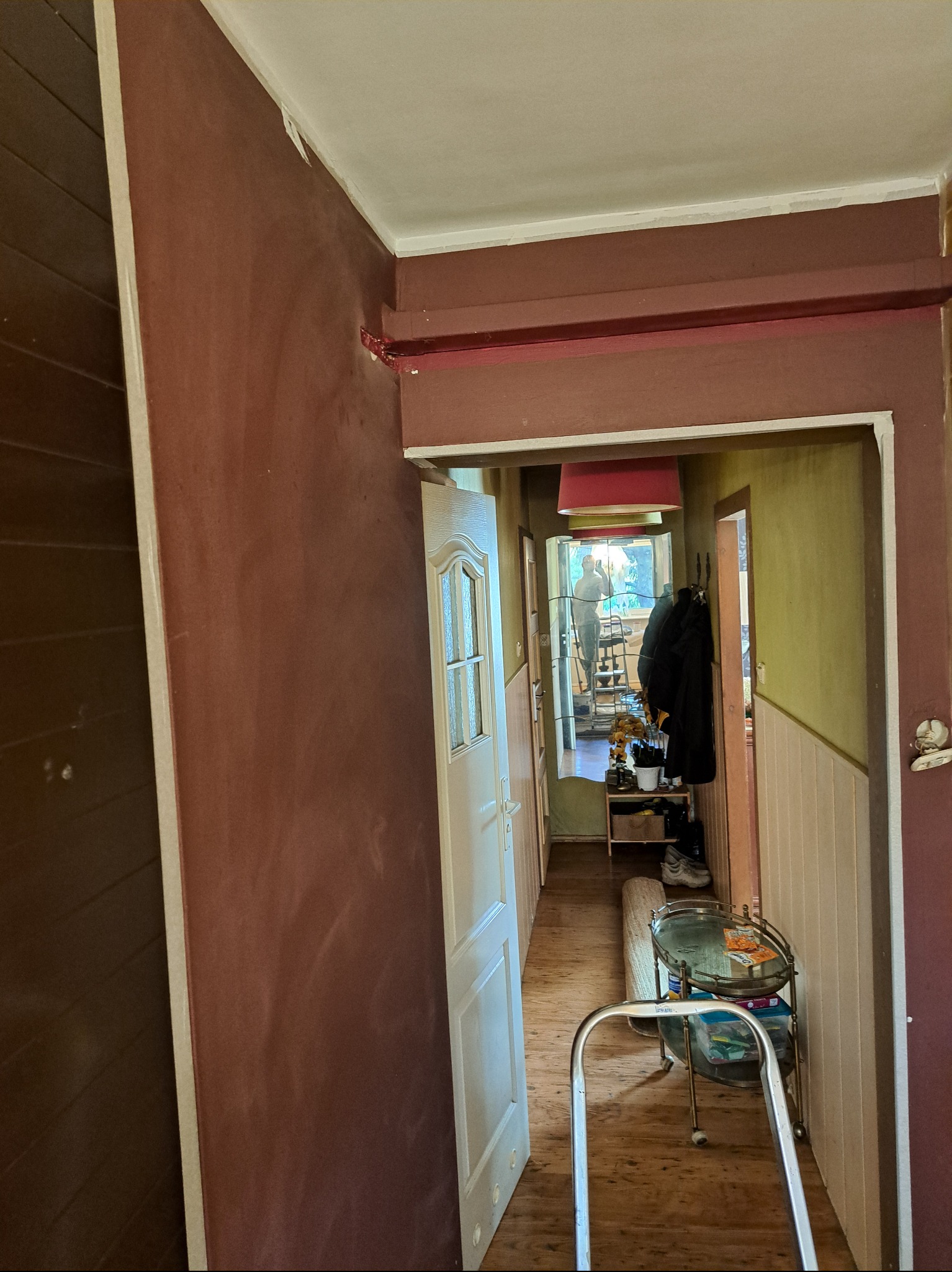 Korytarz po odświeżeniu ścian w odcieniach brązu i beżu. Widoczna drabina malarska i stolik na kółkach. W głębi lustro z odbiciem osoby.