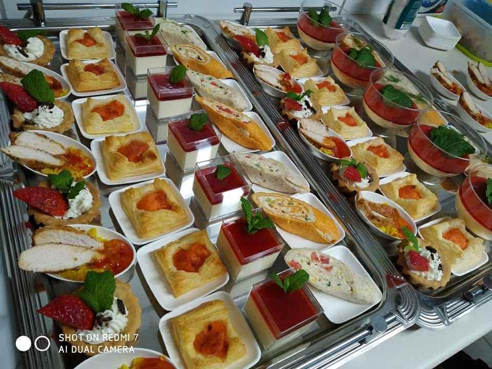 Elegancki catering: różnorodne przekąski finger food na srebrnych tacach. Puff pastry z nadzieniem, roladki, desery w szklankach i tartaletki z owocami, dekorowane miętą.