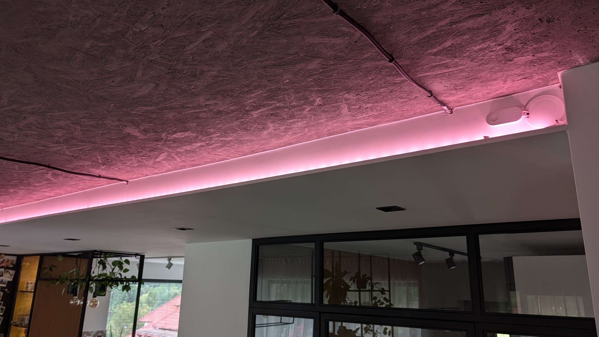 Nowoczesne oświetlenie LED z różową poświatą zamontowane w suficie podwieszanym w Wieliczce. Widoczne przewody elektryczne i czujnik.