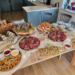 À la main party box & catering - Stół z różnorodnym, estetycznie podanym cateringiem: burgery, przekąski warzywne, tacos, pierożki, sosy i świeczki. Idealne na imprezę firmową lub świąteczną.