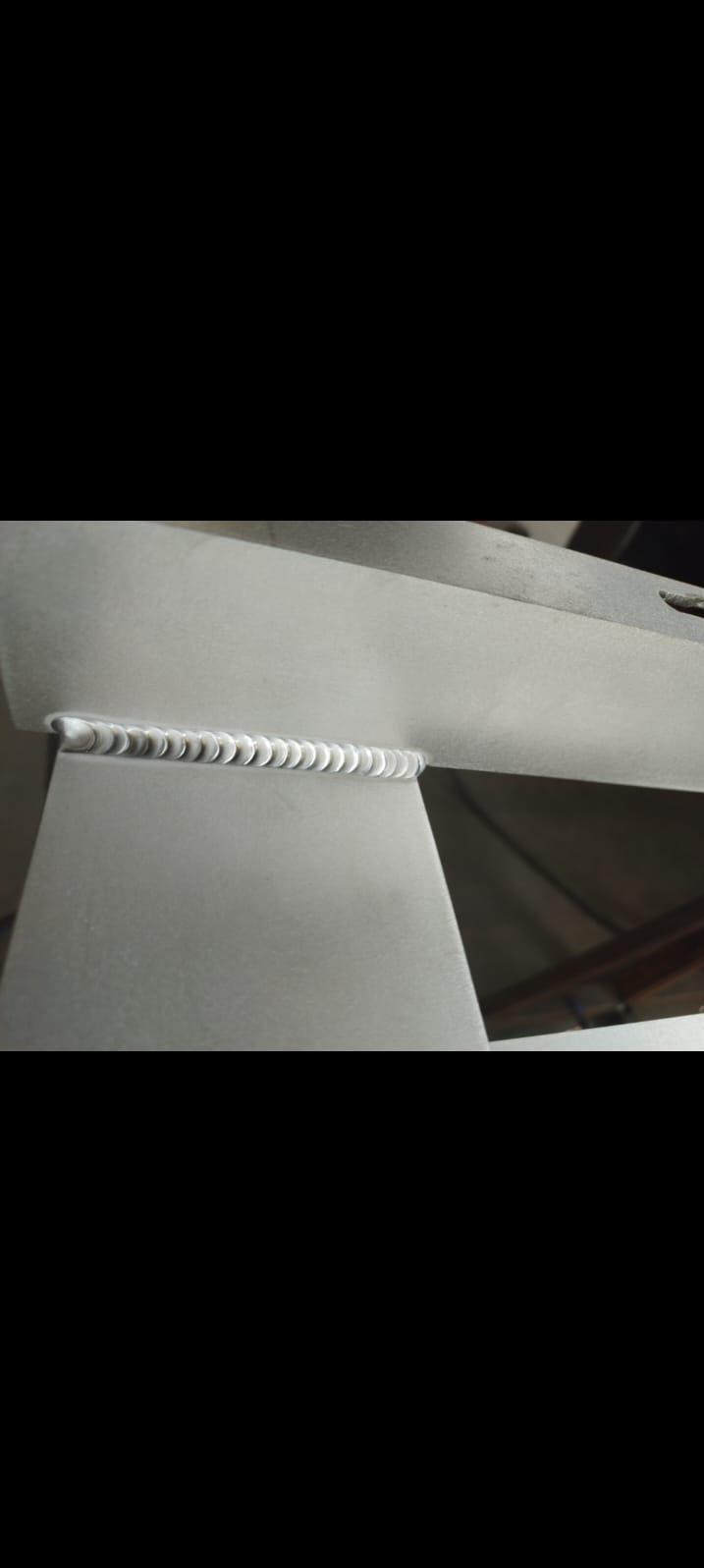 Precyzyjne spawy na metalowej konstrukcji. Widoczna spoina w kształcie łezek, świadcząca o wysokiej jakości wykonania. Detal z bliska, z wyraźną fakturą metalu.