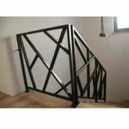 Nowoczesna, czarna balustrada schodowa o geometrycznym wzorze. Metalowa konstrukcja z ukośnymi prętami, zamontowana przy schodach w jasnym wnętrzu.