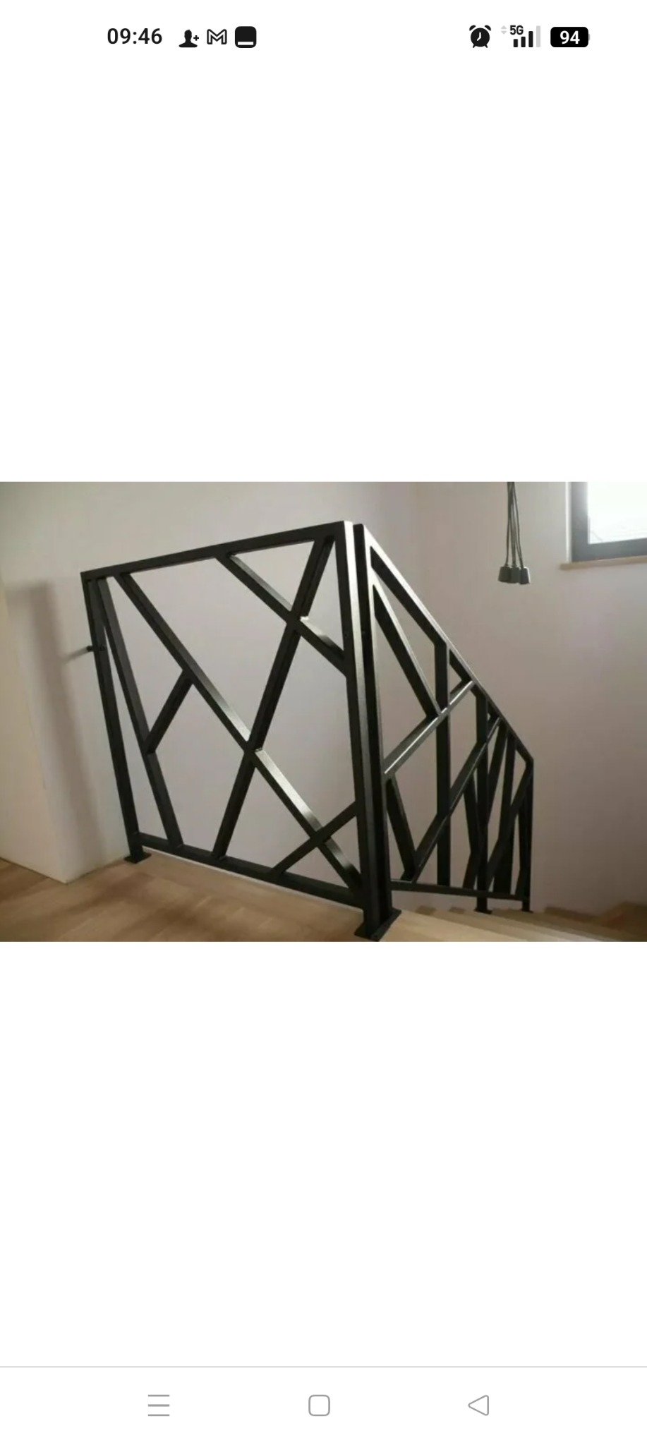 Nowoczesna, czarna balustrada schodowa o geometrycznym wzorze. Metalowa konstrukcja z ukośnymi prętami, zamontowana przy schodach w jasnym wnętrzu.