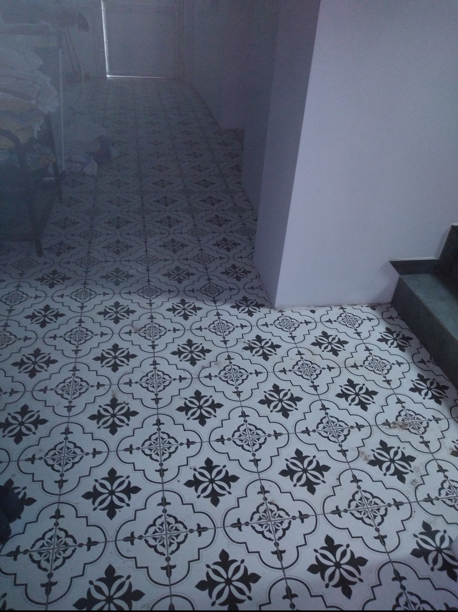 Ułożona podłoga z czarno-białych płytek w geometryczny wzór. Realizacja w Świnoujściu. Widoczne fragmenty ściany i schodów.