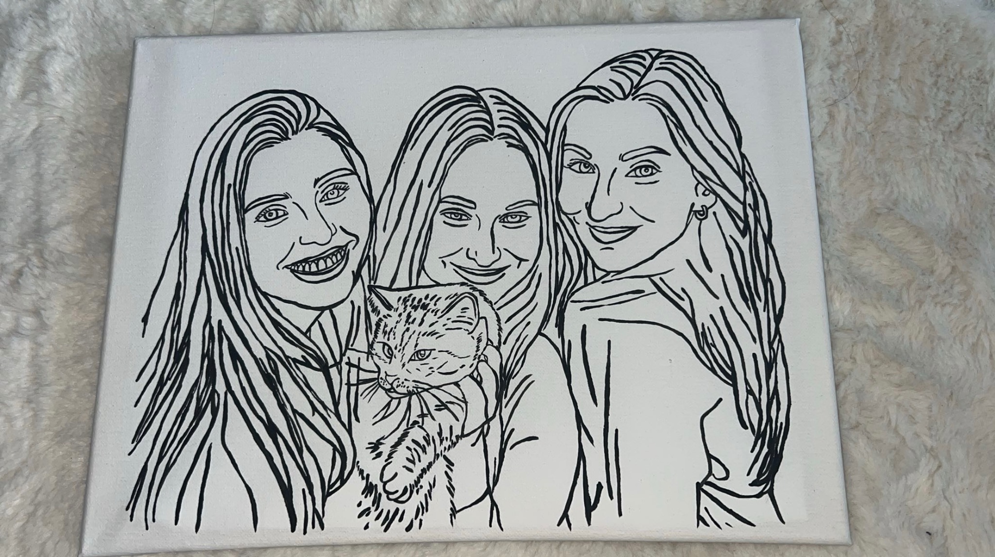 Ręcznie malowany portret linearny na płótnie, przedstawiający trzy uśmiechnięte kobiety i kota. Czarno-biała grafika na tle puszystego koca.