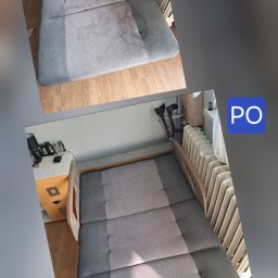 Ogarnij To - Dwa ujęcia tapczanu: górne z plamami, dolne po czyszczeniu, ukazujące odświeżoną szarą tapicerkę. Widoczne elementy otoczenia: grzejnik, szafka nocna.