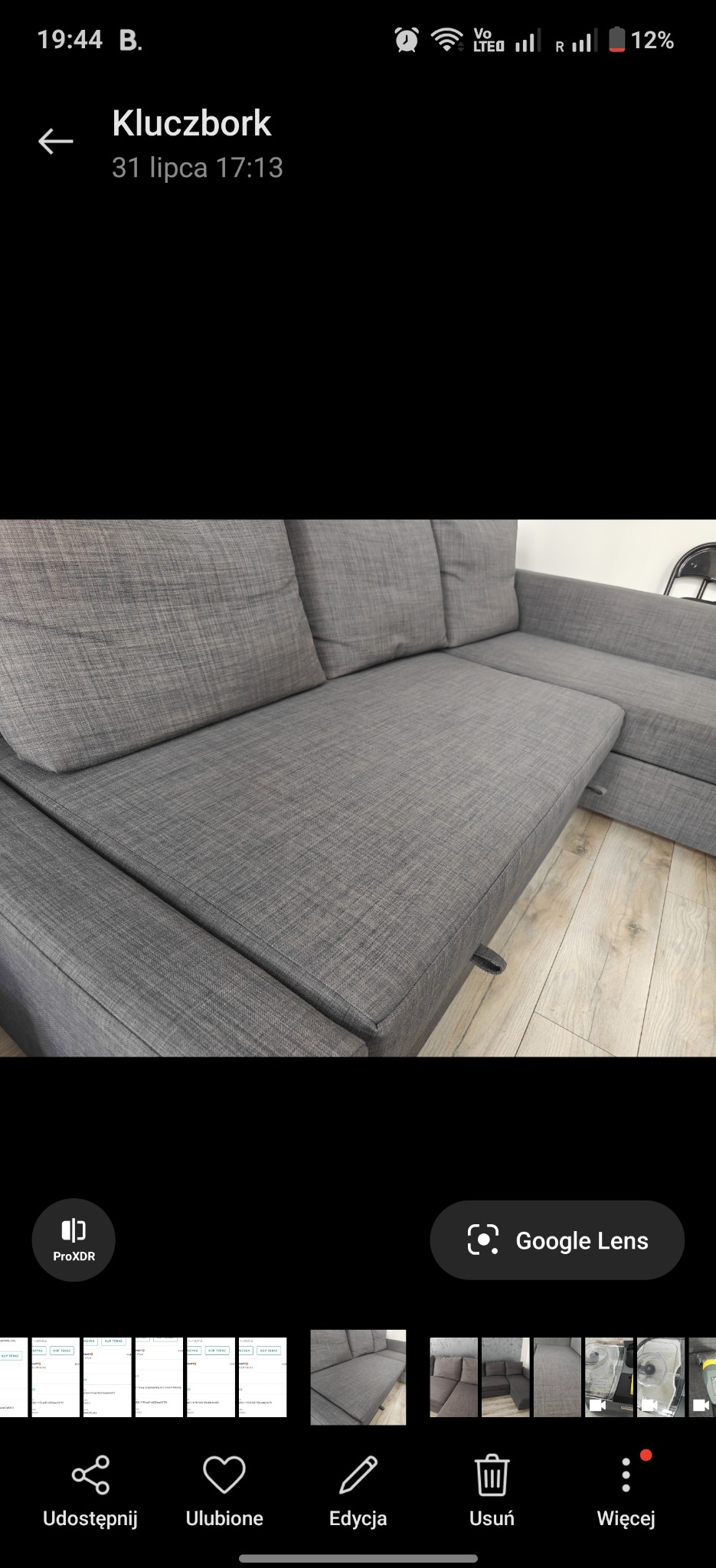 Szara, narożna kanapa z poduszkami, widoczna z bliska, po praniu. Parkiet na podłodze. Zdjęcie zrobione z lekkiego ukosa, ukazujące detale tkaniny i kształt mebla.