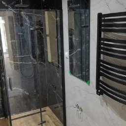 Remont Plus Łukasz - Nowoczesna kabina prysznicowa z czarnymi elementami i imitacją marmuru w Kielcach, uzupełniona o lustro i grzejnik drabinkowy.