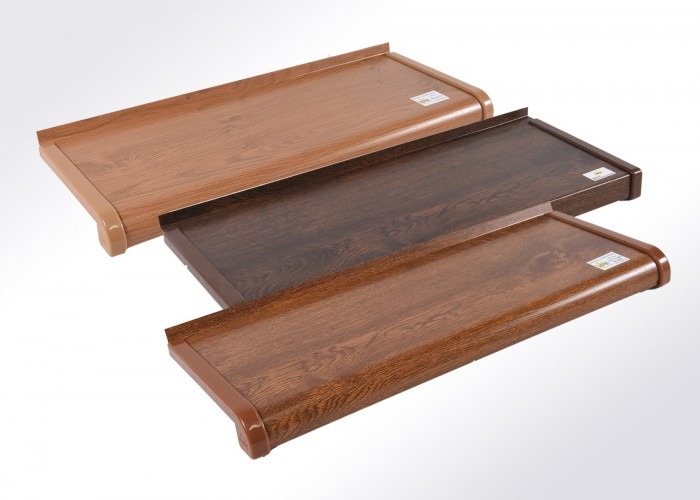 Trzy parapety okienne PCV w odcieniach brązu, każdy z widoczną strukturą drewna i zaokrąglonym profilem, ułożone kaskadowo na białym tle. Prezentacja różnych wariantów kolorystycznych.