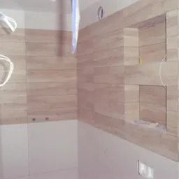 Niedokończona łazienka z poziomymi płytkami imitującymi drewno, wnęka w ścianie, wystające kable elektryczne i przewody hydrauliczne.