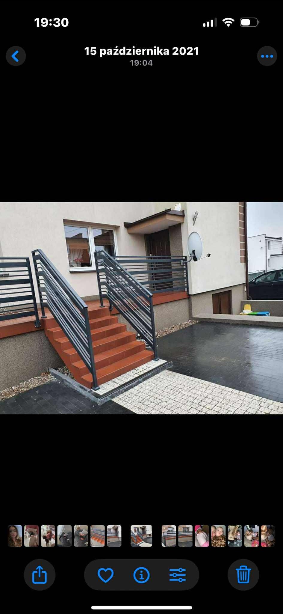 Metalowe balustrady schodowe w nowoczesnym stylu, z poziomymi szczeblami, prowadzące do wejścia domu. Ujęcie z dołu, widoczne schody z terakoty i kostka brukowa.