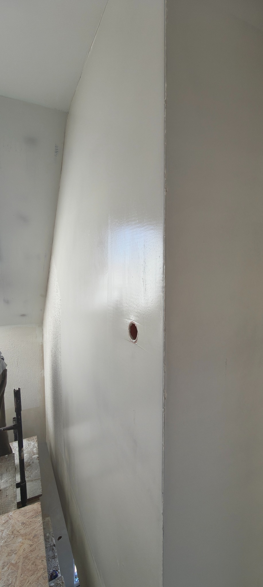 Gładka, świeżo pomalowana ściana z otworem na gniazdko elektryczne w Pisz. Widoczne ślady po szpachlowaniu i przygotowaniu do malowania.