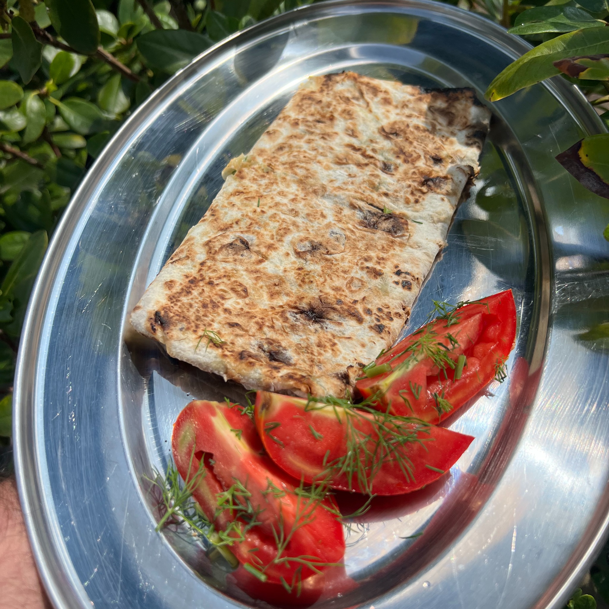 Placek z pomidorami i koperkiem na srebrnej tacy, Wrocław. Danie gotowe do podania, otoczone zielenią. Idealne na catering.