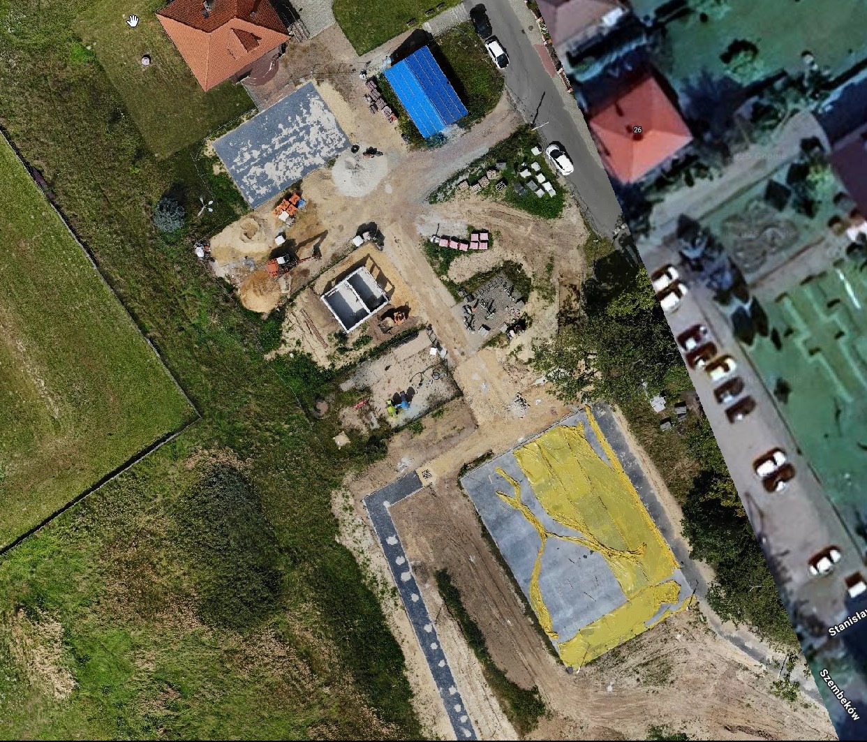 Widok z drona na plac budowy domu jednorodzinnego w trakcie wznoszenia fundamentów, z widocznym zbrojeniem i częściowo wylanym betonem.