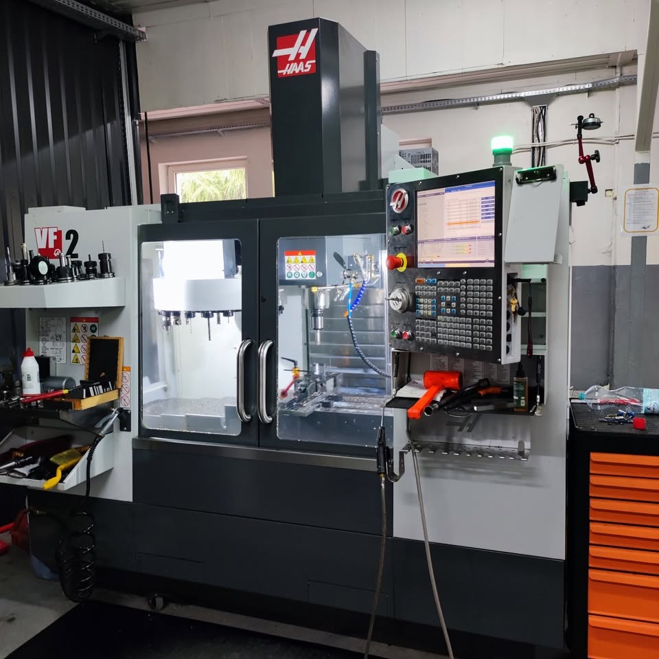 Nowoczesna frezarka CNC Haas VF-2 w warsztacie, widoczne narzędzia i panel sterowania. Maszyna gotowa do obróbki metalu.