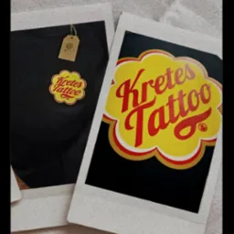 Dwa zdjęcia polaroidowe: jedno z czarną koszulką z nadrukiem, drugie z grafiką 'Kretes Tattoo' w stylu lizaka Chupa Chups. Stonowane tło.