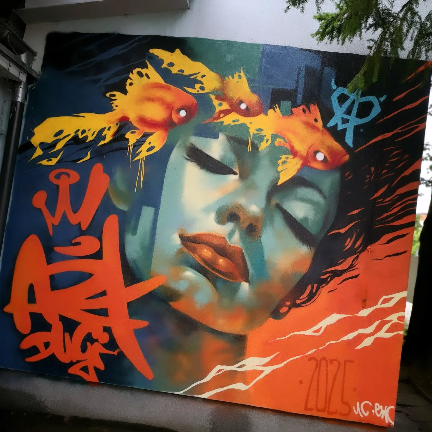 Unikatowe malowidło: portret kobiety z zamkniętymi oczami, nad którą unoszą się trzy złote rybki. Wyraziste kolory, graffiti i sygnatura artysty w prawym dolnym rogu.