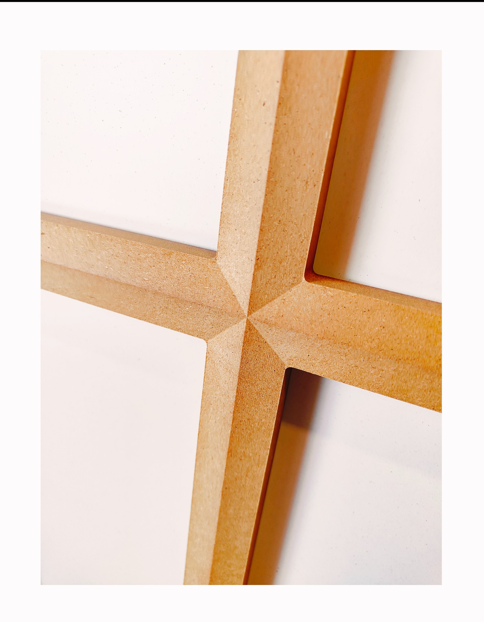 Precyzyjnie wycięty, drewniany krzyż z MDF, z widoczną strukturą materiału i fazowanymi krawędziami, na gładkim, białym tle. Detal obróbki.