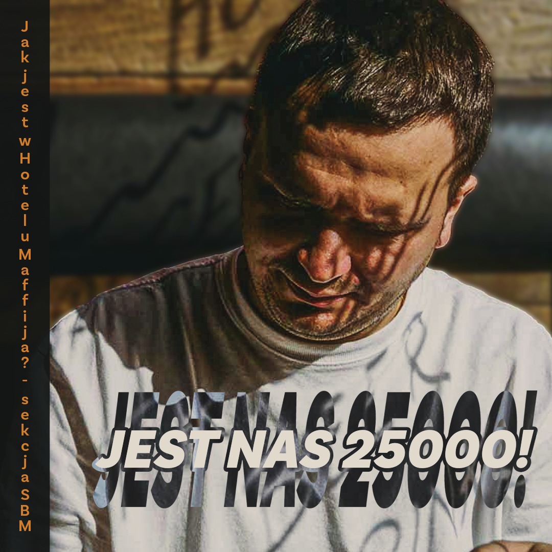 Mężczyzna w koszulce z napisem 'JEST NAS 25000!' w miejskim otoczeniu, oświetlony światłem słonecznym.