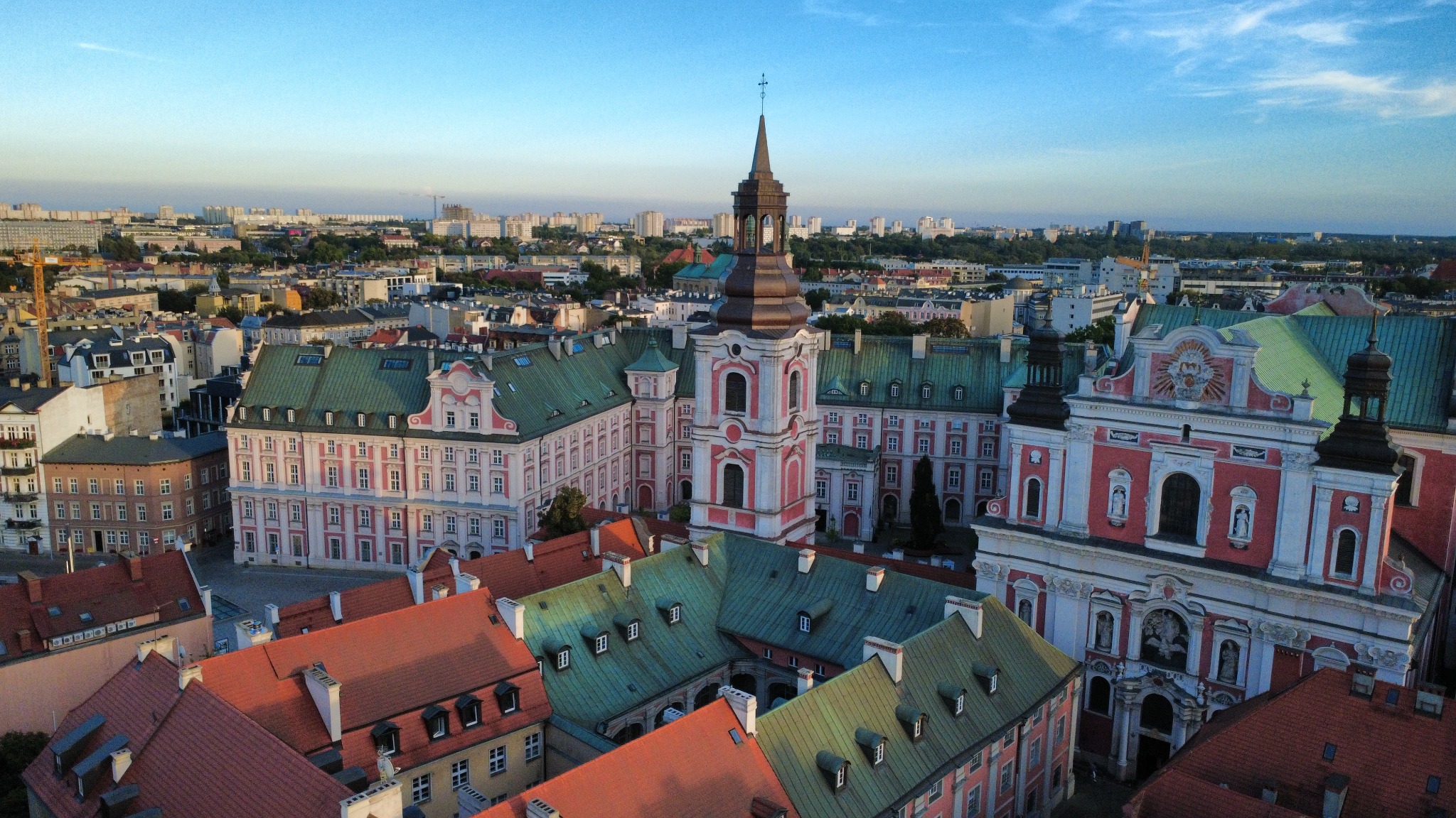 Panorama Poznania z widokiem na barokowy kościół i zabudowę Starego Miasta, sfotografowana z lotu ptaka w słoneczny dzień.