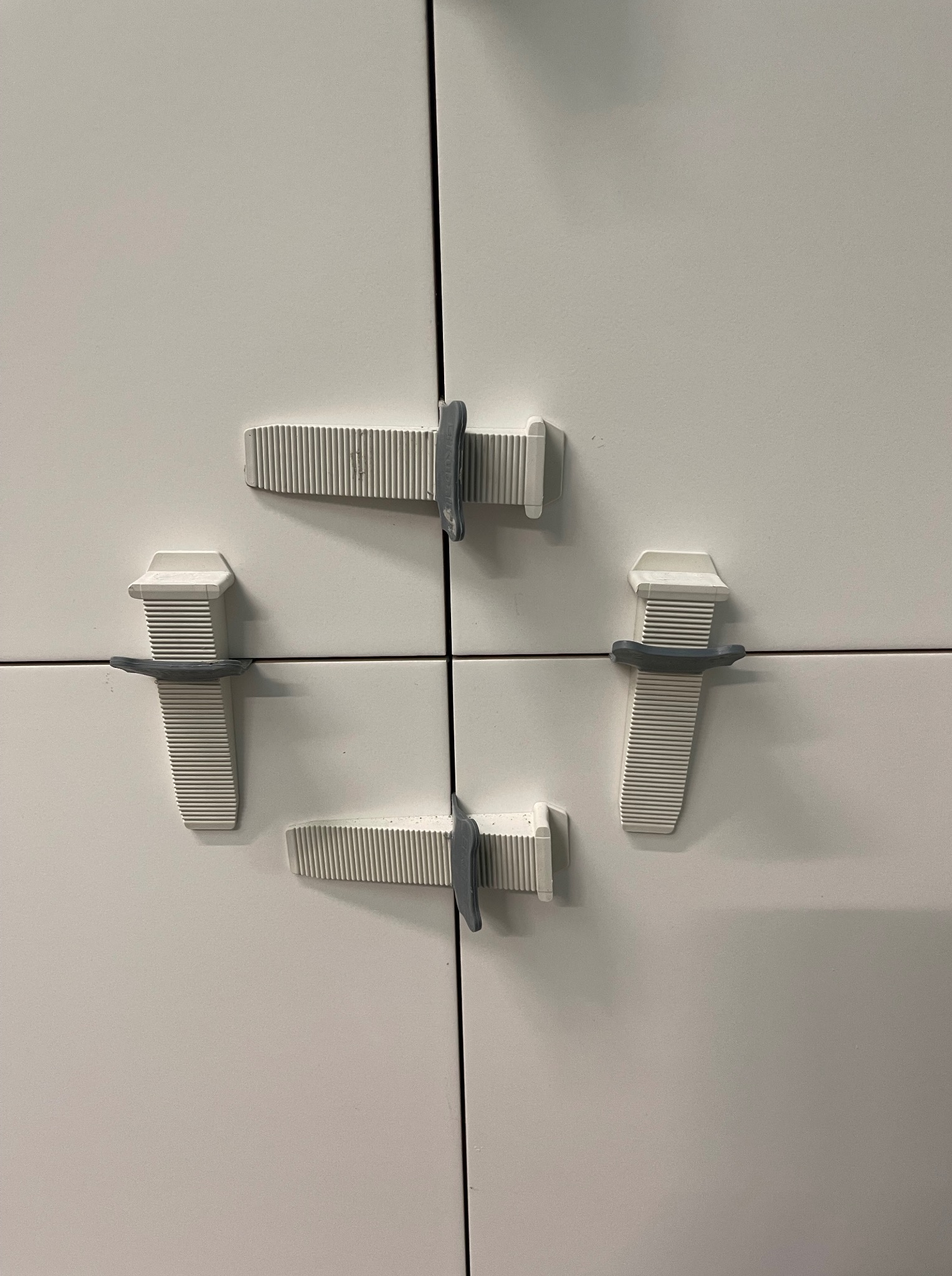 Białe płytki wyrównane za pomocą klipsów i klinów, tworzące równą powierzchnię. Detal z bliska, pokazujący etap prac wykończeniowych.