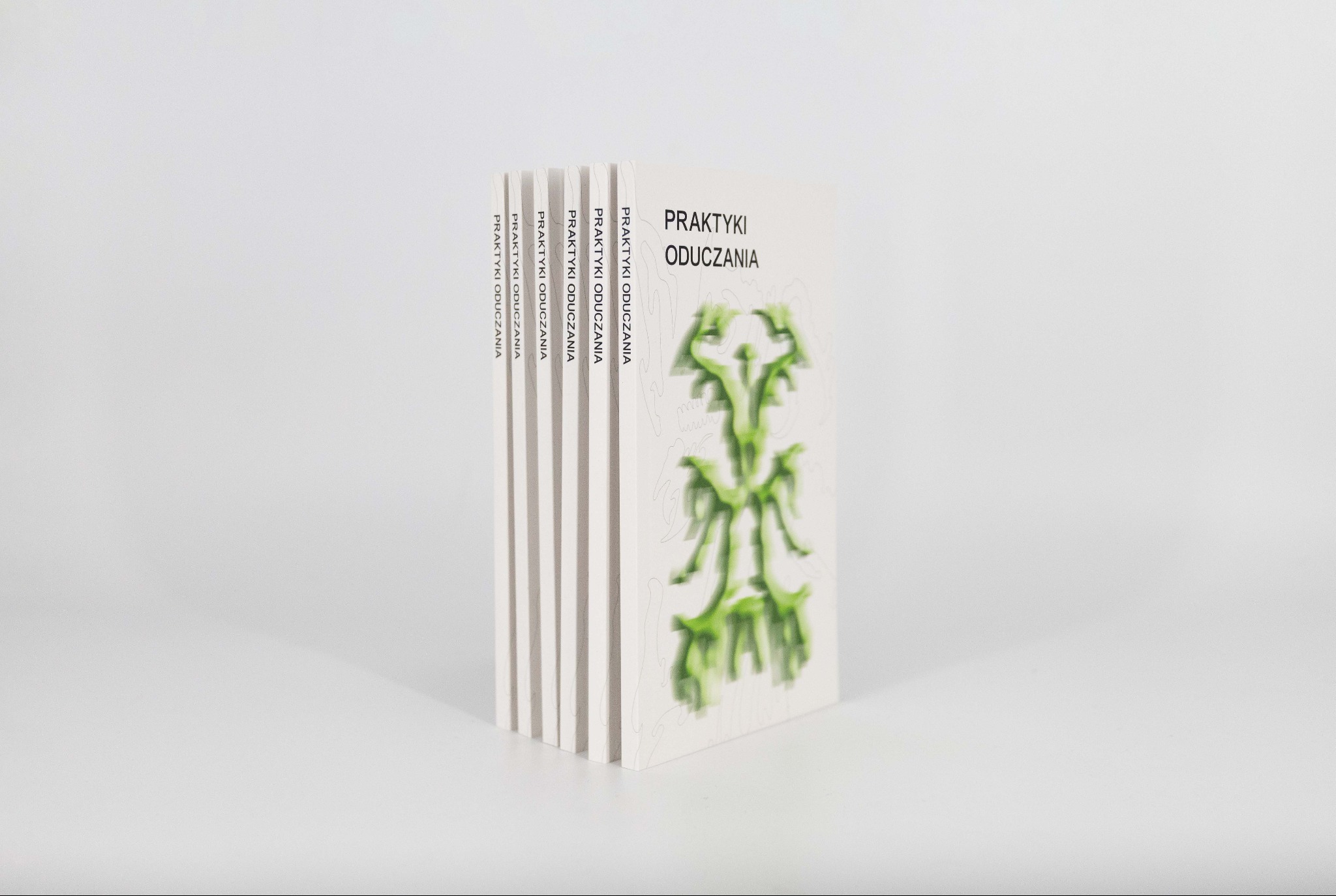 Książki z okładką 'Praktyki oduczania' ustawione pionowo, eksponujące tytuł i grafikę. Minimalistyczne tło, stonowana kolorystyka, podkreśla artystyczny charakter publikacji.