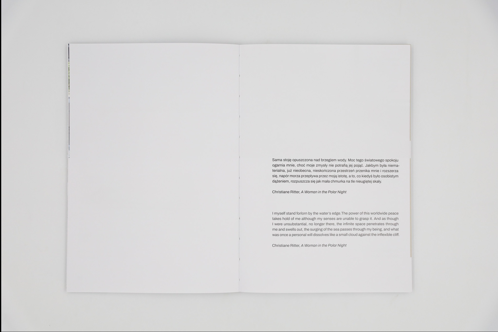 Rozłożona książka z tekstem w języku polskim i angielskim, leżąca na białym tle. Fragment tekstu autorstwa Christiane Ritter, 'A Woman in the Polar Night'.