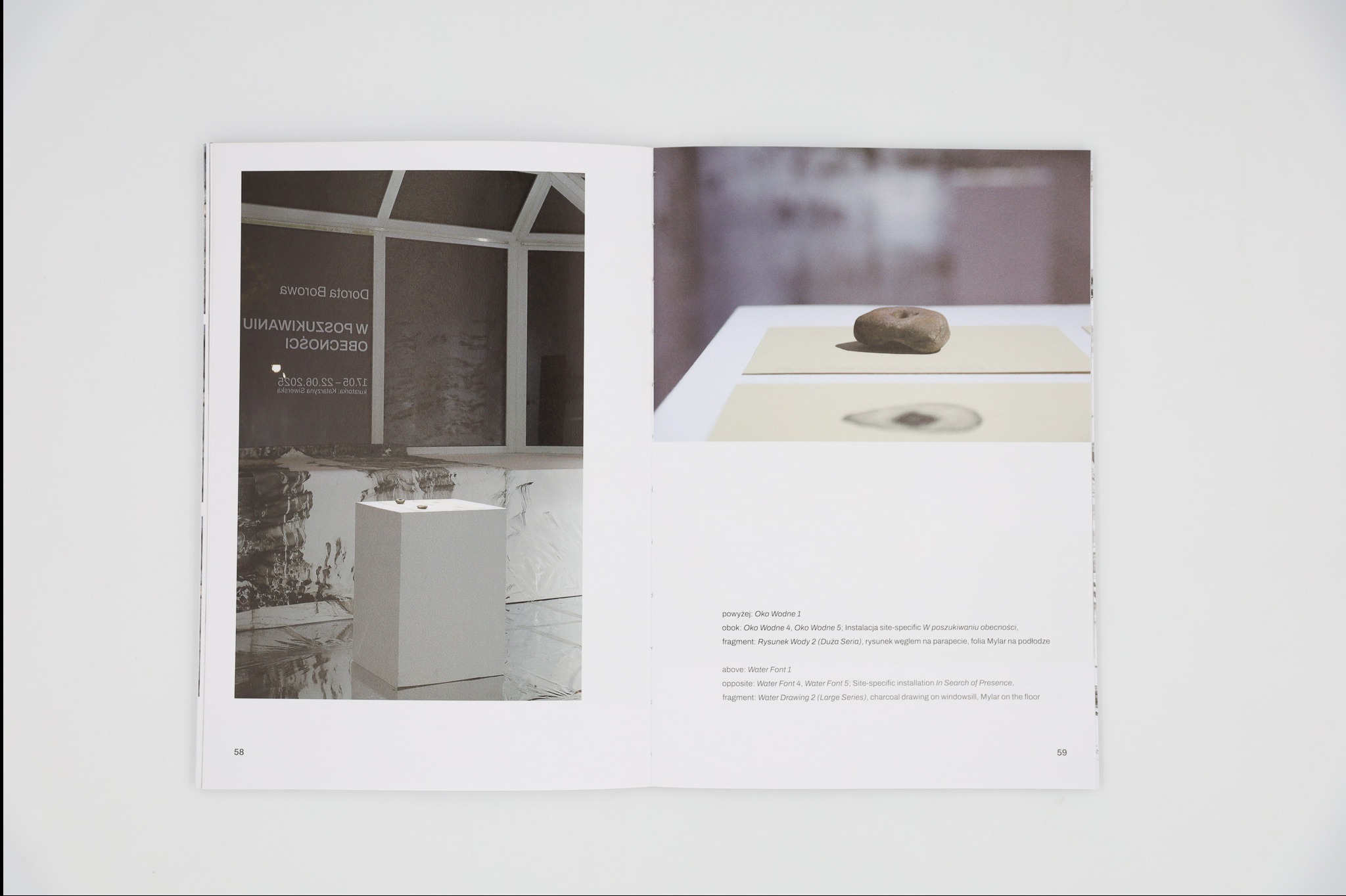 Rozkładówka książki artystycznej prezentująca instalację site-specific z kamieniem na postumencie i rysunkiem węglem. Minimalistyczna kompozycja w jasnej tonacji.