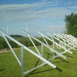 KD PRODUCTS Klaudia Gniazdowska - Metalowa konstrukcja wsporcza na trawniku w Złotowie, z turbinami wiatrowymi w tle. Solidne, spawane elementy, regularny układ, jasne niebo.