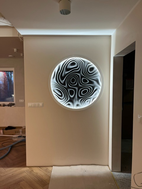 Okrągła, podświetlana dekoracja ścienna z abstrakcyjnym wzorem w wyremontowanym wnętrzu z parkietem i widocznym oknem. Nowoczesny design.