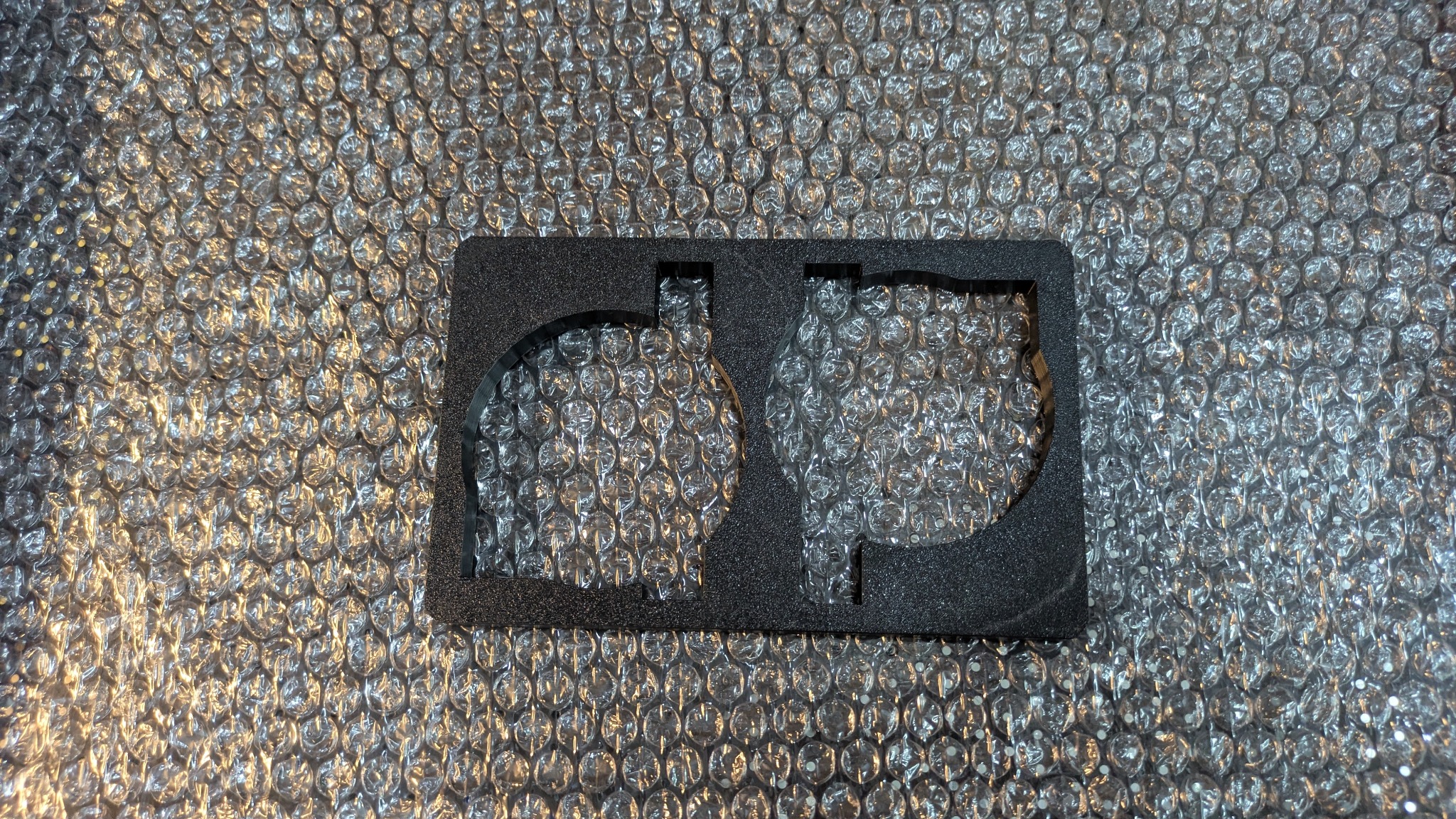 Czarna, piankowa forma z dwoma okrągłymi wycięciami, leżąca na folii bąbelkowej. Detaliczne wykończenie, precyzyjne cięcie.