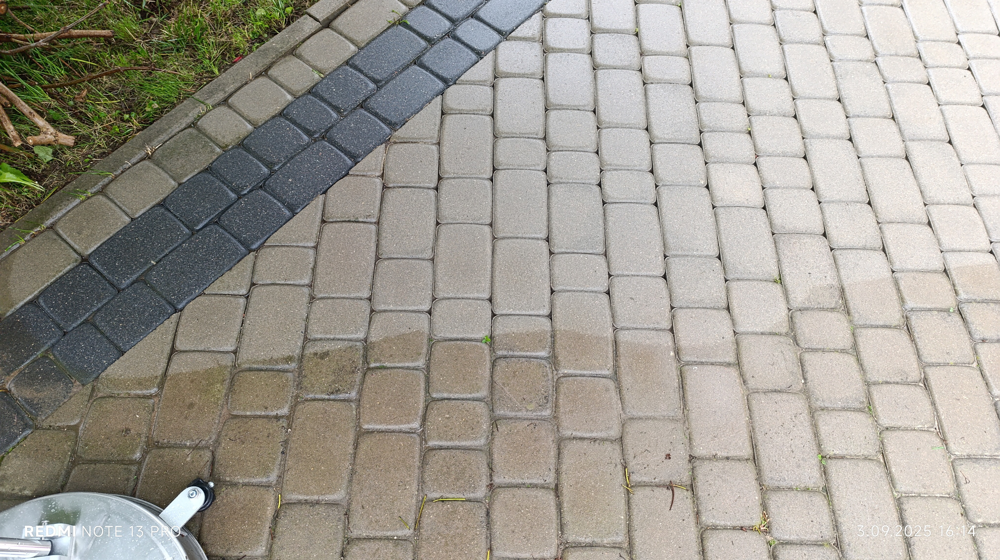 Fragment kostki brukowej, częściowo umytej, z widocznym urządzeniem do czyszczenia. Kontrast czystej i zabrudzonej powierzchni.