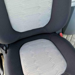 Ekipa czystości - Szczegółowe ujęcie wyczyszczonego, jasnego fotela samochodowego z ciemną obwódką. Widoczna faktura materiału i szwy. Czysty i zadbany wygląd.