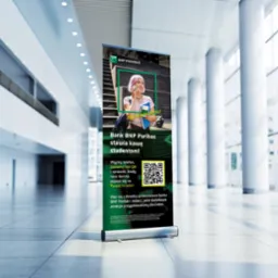 Roll-up Banku BNP Paribas z grafiką studentki i kodem QR na tle nowoczesnego wnętrza z kolumnami i dużymi oknami. Kampania reklamowa skierowana do studentów.