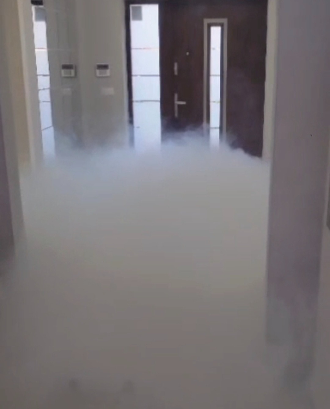 Efekt ciężkiego dymu wypełniającego nowoczesne wnętrze z drzwiami, tworząc unikalną atmosferę. Dekoracja na imprezę z użyciem wytwornicy dymu.