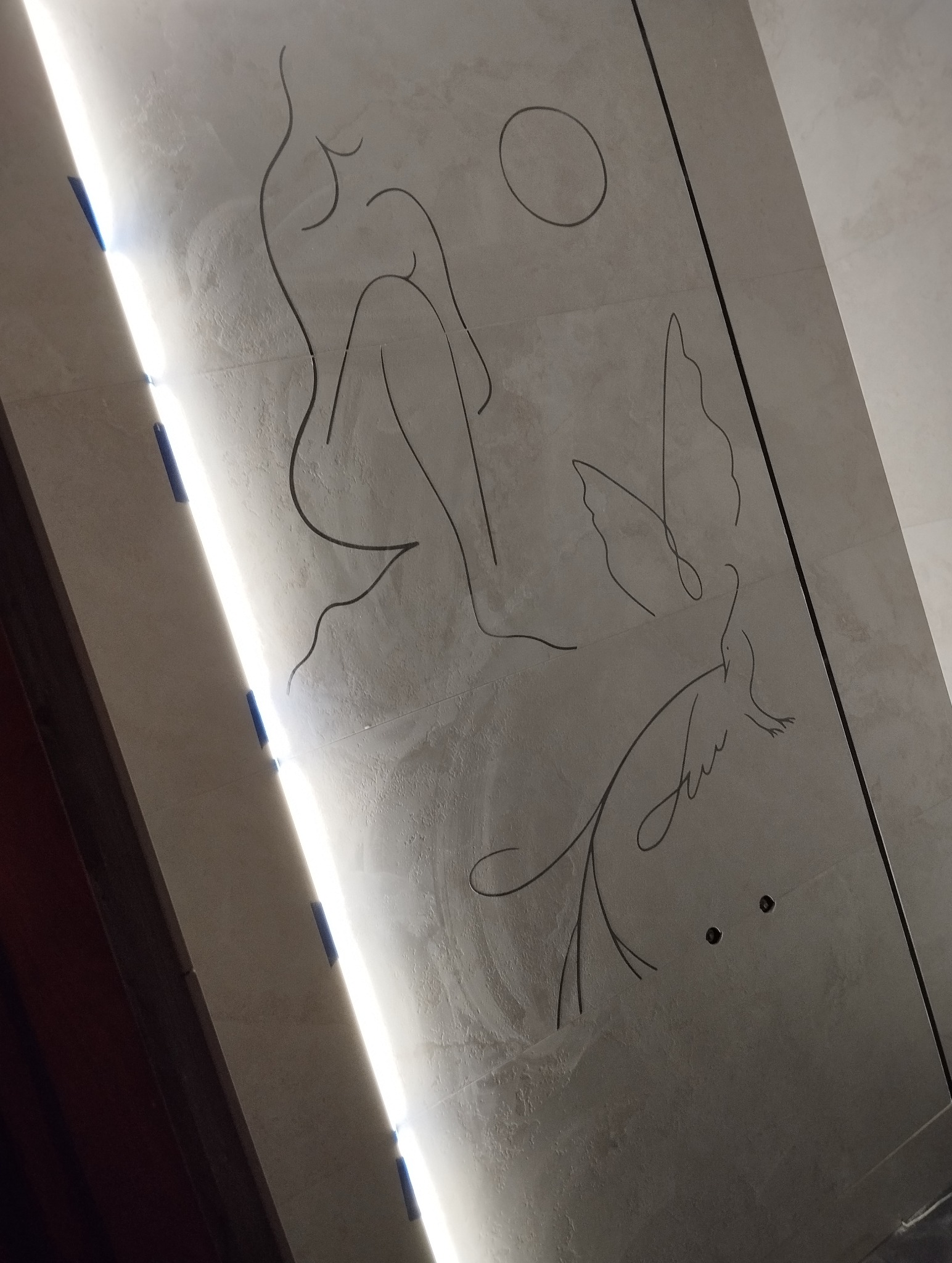 Ściana z abstrakcyjnym rysunkiem kobiety, ptaka i słońca, oświetlona ledowym światłem. Minimalistyczny design w wykończeniu wnętrza.